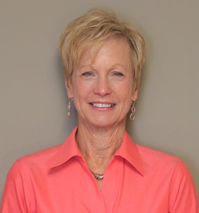 A woman in an orange shirt smiling for the camera.