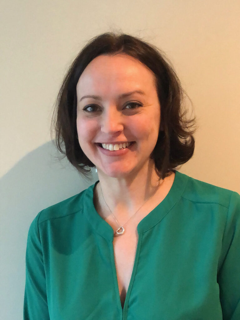 A woman in green shirt smiling for the camera.