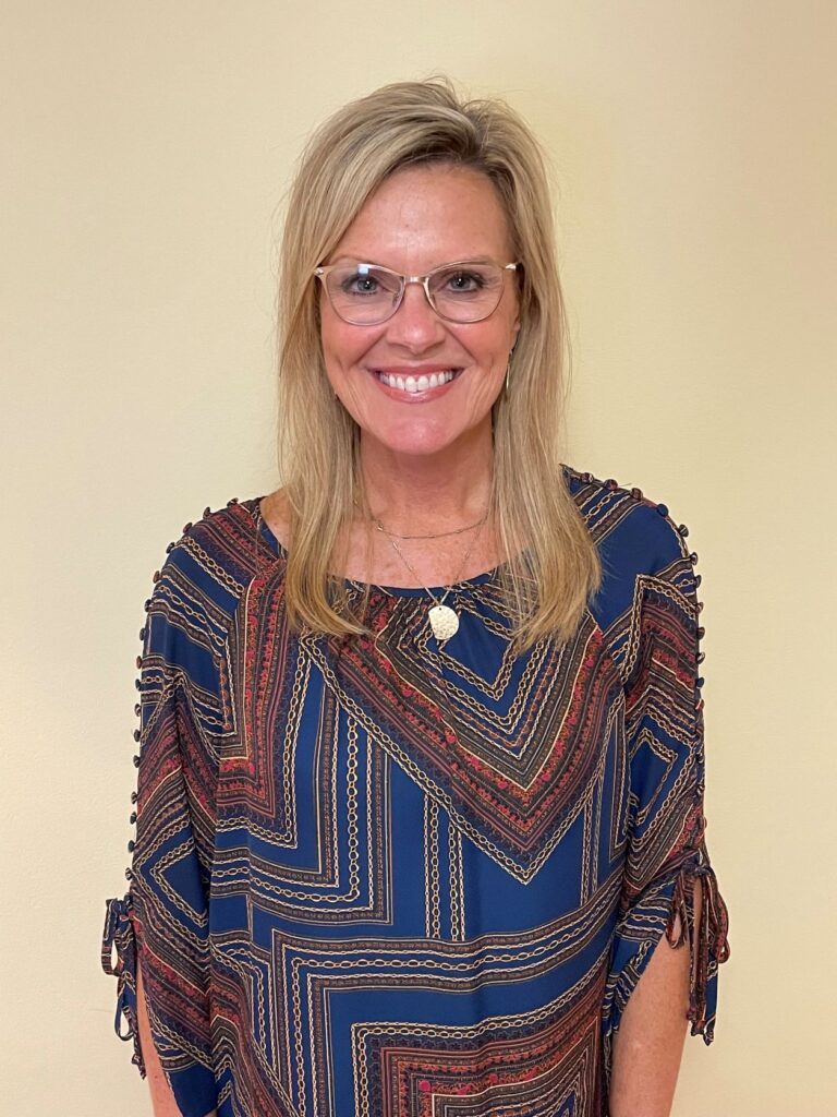 A woman wearing glasses and smiling for the camera.